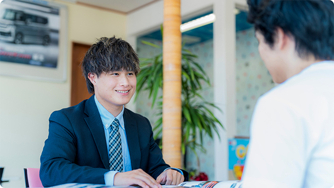 お客と会話をしているスーツ姿の男性